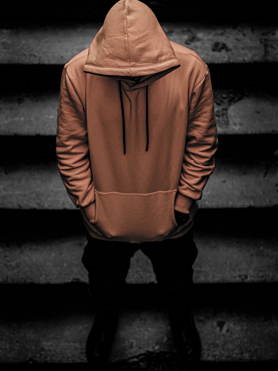 Adult model style reference — person in brown hoodie and black pants standing on staircase